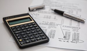 A calculator with a printed balance sheet, written on in pen.  An uncapped pen is on the balance sheet.