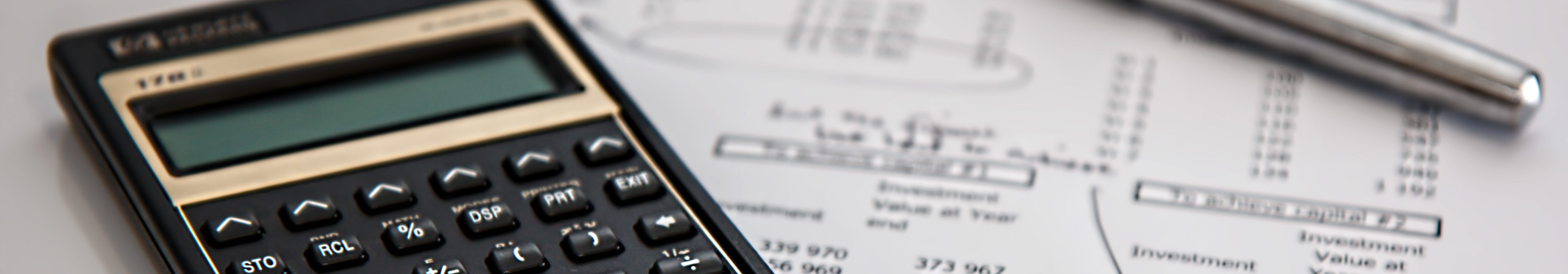 A calculator on a printed balance sheet.  The balance sheet is marked up in pen, and the pen is on the sheet.