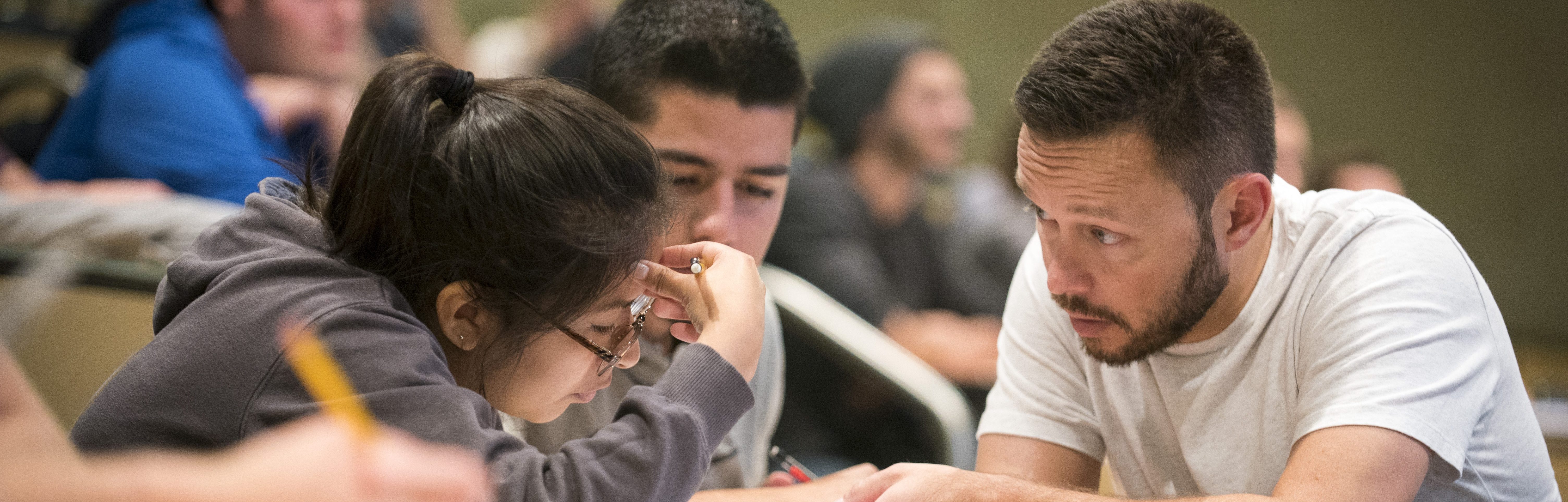Graduate student aiding students during a professor's lecture.