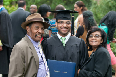 Two parents and their graduating student, smiling proudly.